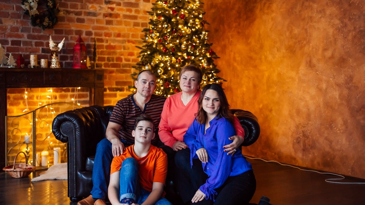 a family poses in front of a christmas tree